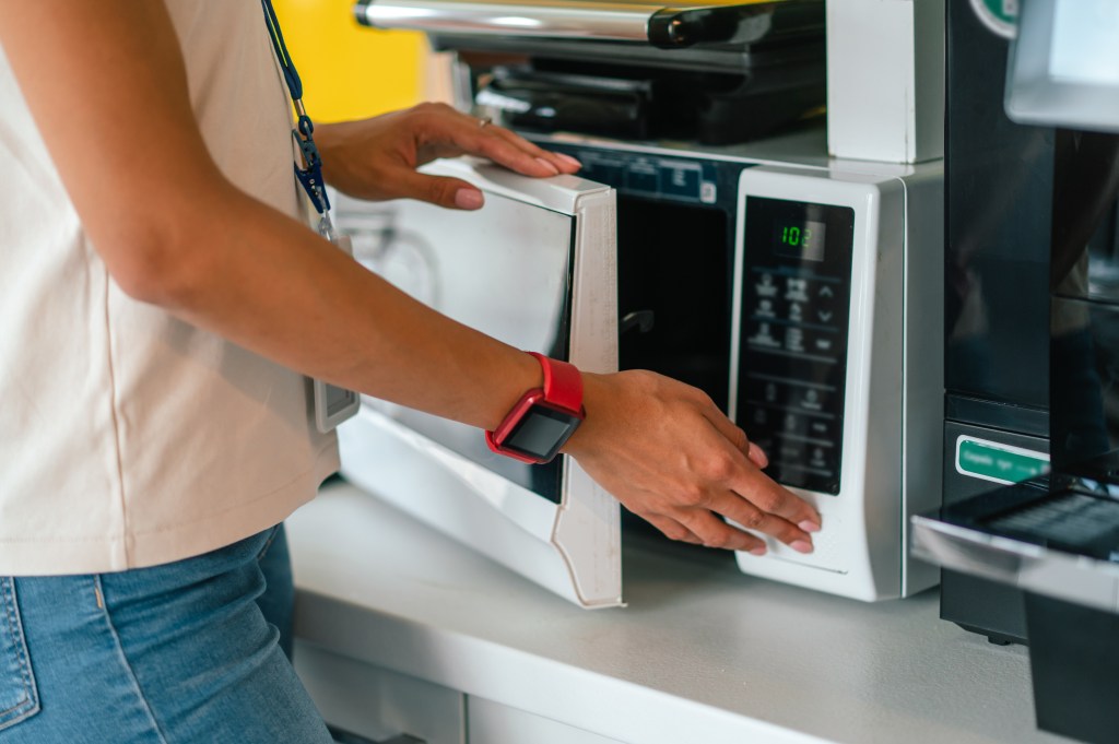 According to experts, microwaves can be breeding bases for bacteria. Here, person at work opening microwaves.