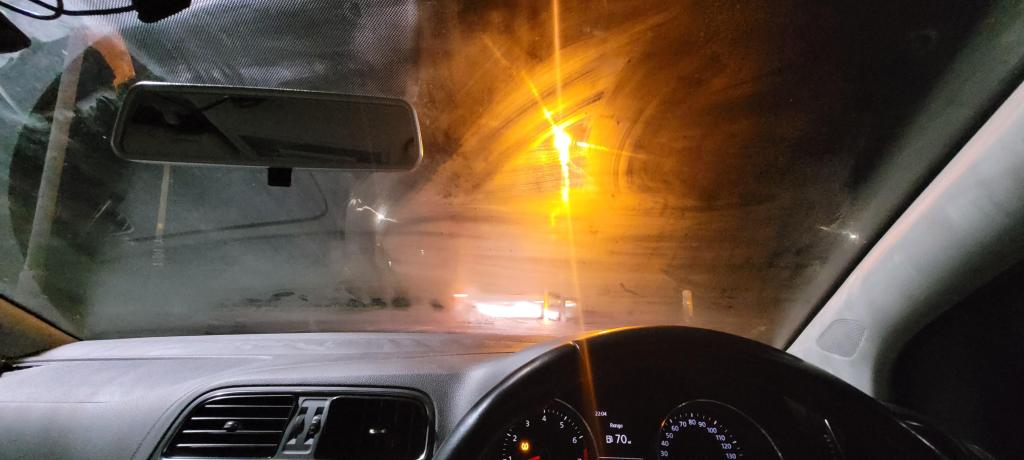 Car glass darkened by evaporation residues, causing shine and visibility issues